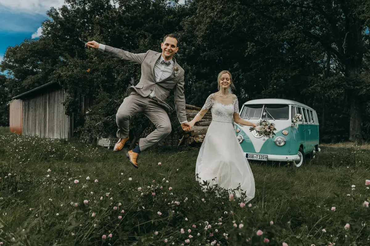 Ein Hochzeitspaar feiert neben seinem Hochzeitsbulli