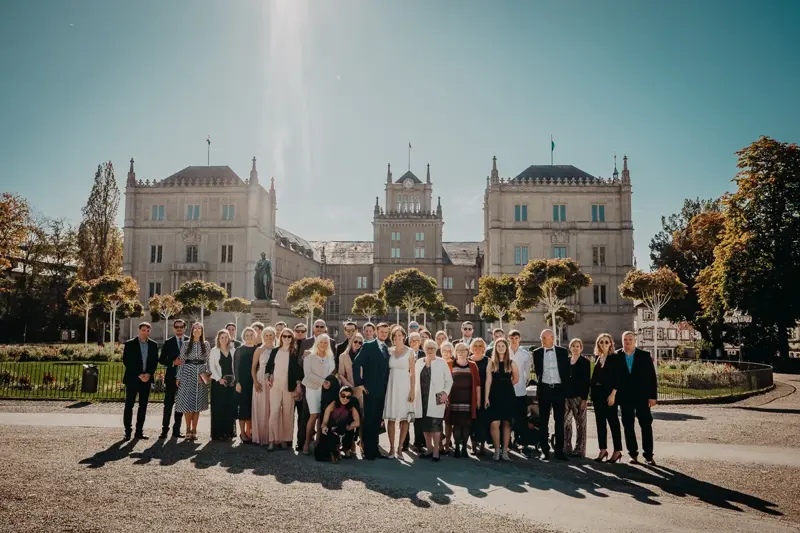 Eine Hochzeitsgesellschaft vor einer historischen Schlossfassade